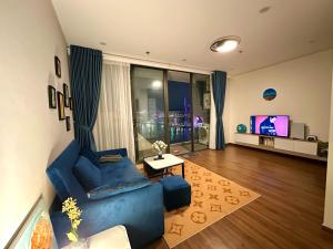 ein Wohnzimmer mit einem blauen Sofa und einem TV in der Unterkunft Green Diamond Homestay in Hạ Long