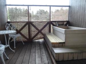 a tub on a wooden deck with a table and chairs at IZUNA INN & SPA - the veggie delights in Ito