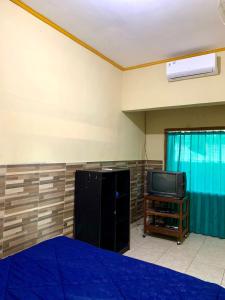 um quarto com uma cama e uma televisão em Penginapan Sedap Malam em Lovina