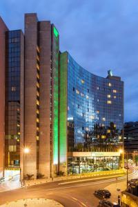 un grande edificio con luci verdi sul lato di Holiday Inn Lisbon-Continental, an IHG Hotel a Lisbona