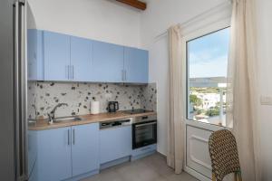 a kitchen with white cabinets and a large window at Μπαλκόνι με θέα / Viewtiful balcony in Adamas