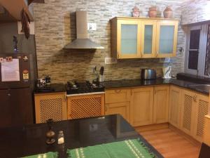 a kitchen with wooden cabinets and a black refrigerator at Well-equipped modern flat with 24/7 security in Srinagar