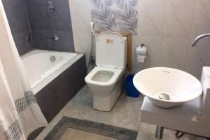 a bathroom with a toilet and a tub and a sink at Well-equipped modern flat with 24/7 security in Srinagar