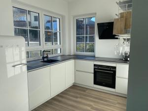 a kitchen with white cabinets and a sink and windows at Das Bad Wiessee 22 in Bad Wiessee