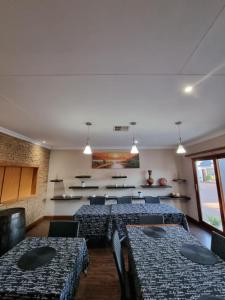 uma sala de jantar com mesas, cadeiras e luzes em The Cape Lodge em Upington
