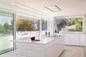 eine Küche mit weißen Schränken und großen Fenstern in der Unterkunft VILLA ILLA BLANCA in Tamariu