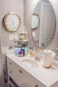 a bathroom with a sink and two clocks on the wall at Country Cottage - Broussard in Broussard