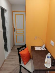 Zimmer mit einem Tisch und einem Stuhl mit orangefarbenem Kissen in der Unterkunft AU CLOS DE L'ETANG in Ravel