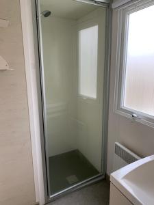 a glass shower in a bathroom with a window at Camping Riva Bella in Ouistreham