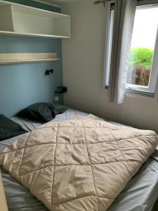 een bed met een dekbed in een slaapkamer bij Camping Riva Bella in Ouistreham