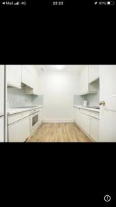 an empty kitchen with white cabinets and a wooden floor at Oxford Street Two Bed Apartment in London