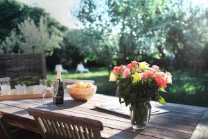a wooden table with a vase of flowers and a bottle of wine at Strandhaus in Hörnum
