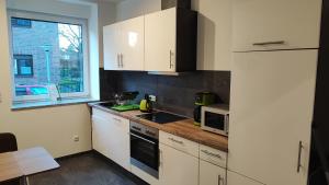 una pequeña cocina con armarios blancos y una ventana en Dammstraße 24-OG-ZV38, en Salzgitter 15 fotos más