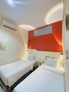 two beds in a room with a red wall at JIYO BOUTIQUE HOTEL by SAJIWA in Medan
