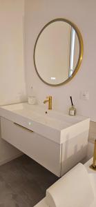 a white bathroom with a sink and a mirror at Douceur Dorée in Yville-sur-Seine