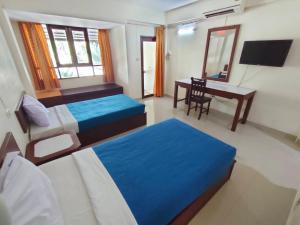 1 dormitorio con 2 camas y escritorio con ordenador en โรงแรมสบายโฮเต็ล 