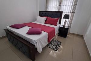 1 dormitorio con 1 cama grande con almohadas rojas y blancas en Spacious Greenery Homely Home, en Ja-Ela
