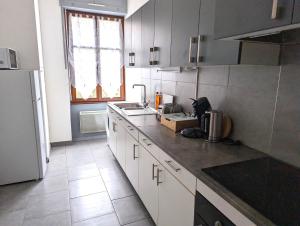 a kitchen with white cabinets and a counter top at Le Mirage - appartement 2 chambres, salon, cuisine équipée, parking et wifi gratuit in Mulhouse +12 photos