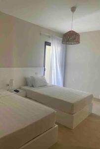 two beds in a white room with a window at Azha 2 bd chalet family only in Ain Sokhna +10 photos