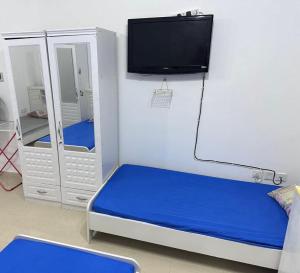 a room with a bed and a tv on a wall at Ladies Hostel in Ajman سكن بنات بعجمان in Ajman 