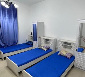 three bunk beds in a room with blue sheets at Ladies Hostel in Ajman سكن بنات بعجمان in Ajman 