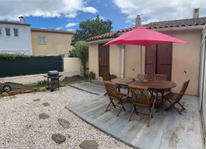 un tavolo in legno con ombrellone rosa in un cortile di Maison avec Piscine privée + Clim proche de la mer a Corneilla-del-Vercol