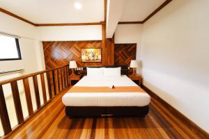 1 dormitorio con 1 cama en una habitación con suelo de madera en Sol Y Viento Mountain Hot Springs Resort, en Calambá