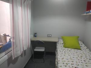 a small room with a bed and a desk with a green pillow at Baix a Mar in Torredembarra