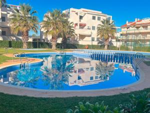 a large swimming pool with palm trees and a building at Apartamentos Las Arenas 3000 in Alcossebre