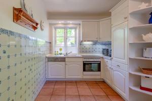 a kitchen with white cabinets and a sink at Annes Cottage 1 in Oevenum