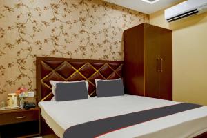 Schlafzimmer mit einem Bett mit einem Kopfteil aus Holz in der Unterkunft Collection O Blue Diamond in Allahabad