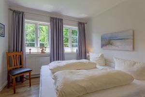 um quarto com 2 camas, uma cadeira e janelas em Annes Cottage 2 em Oevenum