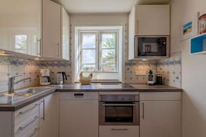 a kitchen with white cabinets and a sink and a window at Annes Cottage 3 in Oevenum
