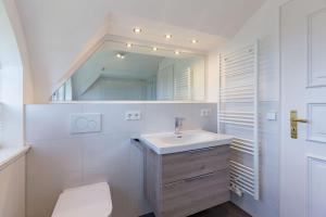 een witte badkamer met een wastafel en een spiegel bij Annes Strandhaus in Wyk auf Föhr