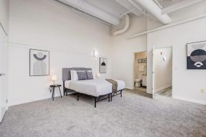1 dormitorio con 1 cama en una habitación blanca en TWO CozySuites Apartment with Skybridge Access #4 en Indianápolis