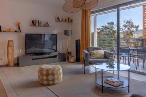 Una sala de estar con un televisor y una mesa y sillas. en Les Terrasses de la Pinède - Appt climatisé, en Coti-Chiavari