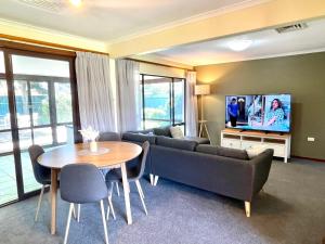 ein Wohnzimmer mit einem Sofa, einem Tisch und einem TV in der Unterkunft Lizzy’s on Lakeside in Lake Albert