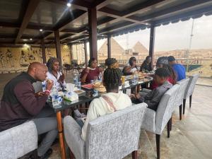 King Pyramids View Hotel في القاهرة: مجموعة من الناس يجلسون على الطاولات يأكلون الطعام
