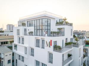 a white building with two people standing on the balcony at M Village Kỳ Đồng in Ho Chi Minh City