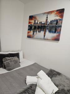 a bedroom with a bed with a picture on the wall at Cozy 1 Bedroom apartment, 30 mins to Oxford street by tube C in London