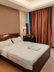 um quarto com uma cama grande e lençóis brancos em Hotel Prima em Sandakan