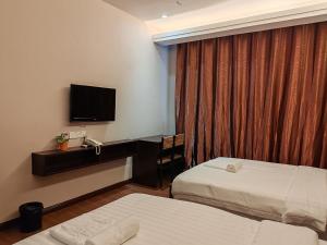 山打根Hotel Prima的一间有两张床和一台平板电视的酒店房间