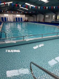 a large swimming pool with blue water in a building at Cosy 2 Bed Chalet in Great Yarmouth