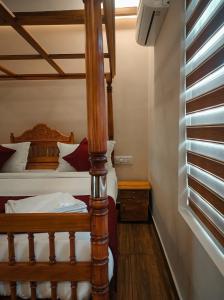 Schlafzimmer mit einem Bett mit Holzpfosten in der Unterkunft ATHIRAPPILY SREENILAYAM HERITAGE RESORt in Athirappilly