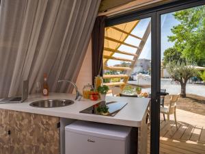 a kitchen with a counter with a sink and a window at Club del Sole Rimini Family Resort in Rimini