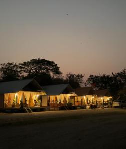 un groupe de tentes dans un champ la nuit dans l'établissement อิงน้ำท่าจีน (ท่าจีนรีสอร์ท), à Suphanburi