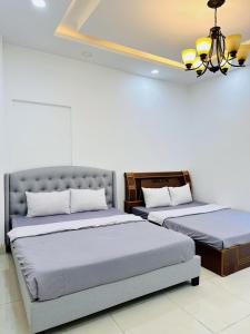 een slaapkamer met 2 bedden en een kroonluchter bij Cactusland Villa Near Bui Vien Street in Ho Chi Minh-stad