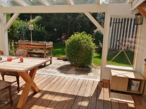 a patio with a wooden table and a large window at Ferienwohnung Hecht - Relax or work in nature in Wolfegg
