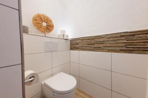 a white bathroom with a toilet and a mirror at Racing-Apartment (Ferienwohnung) in Herresbach