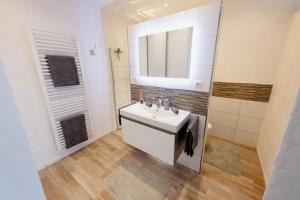 Baño blanco con lavabo y espejo en Racing-Apartment (Ferienwohnung) en Herresbach